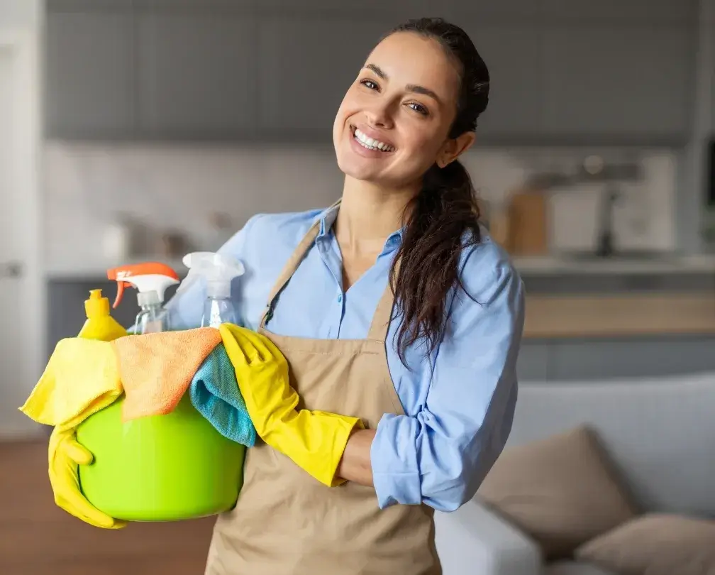 Smiling cleaner holding supplies, representing personalized cleaning plans offered by professional maid services