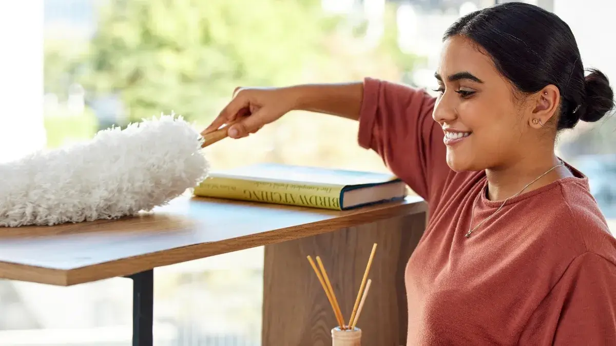 Spring Deep Cleaning by Cali Maids, woman dusting a shelf in a bright home